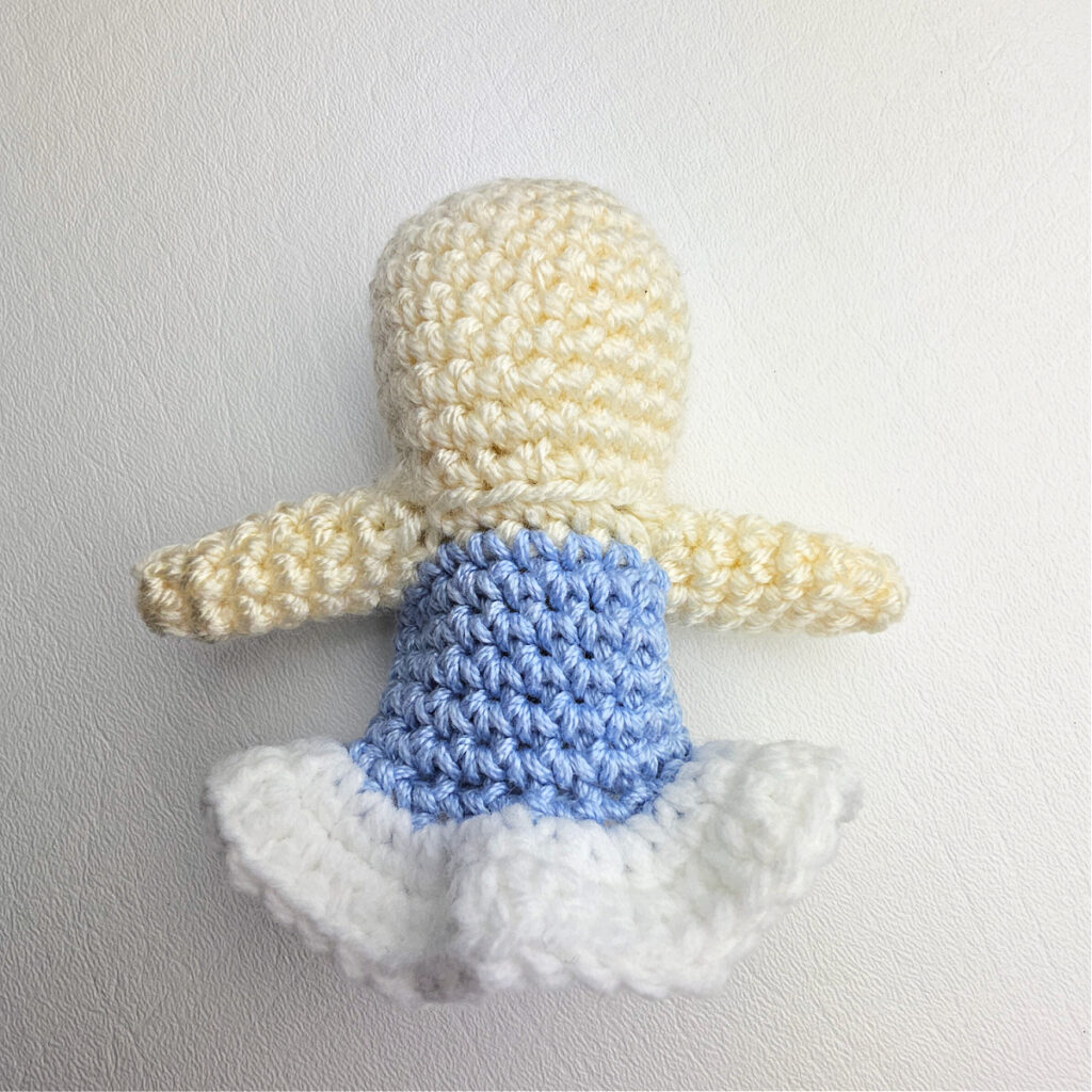 The body of a crochet ballerina amigurumi ornament complete with a blue dress and white tutu.
