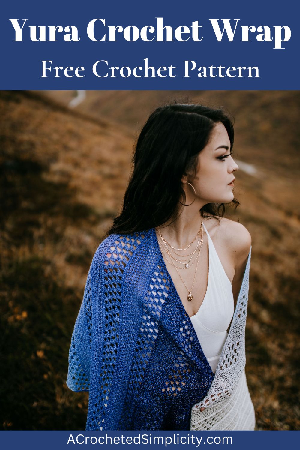 A woman dressed in a white dress and a crochet shawl standing on a hill.