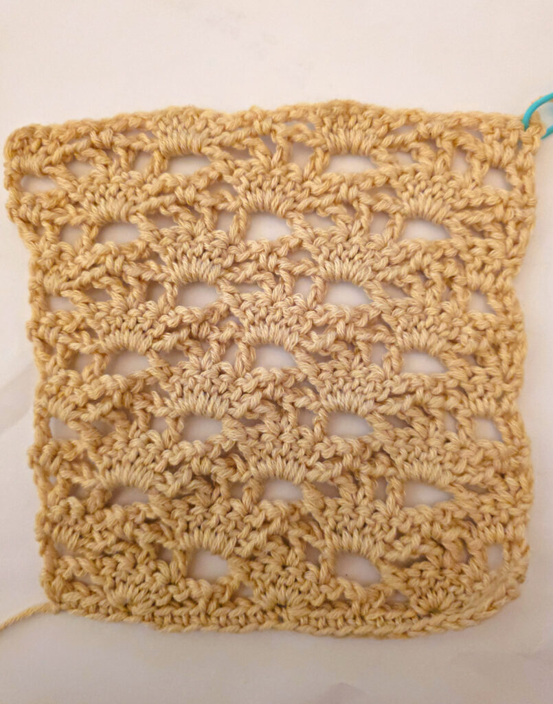 A beige colored cropped crochet cardigan in progress.