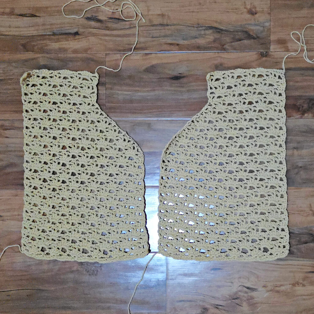 A beige colored cropped crochet cardigan in progress.