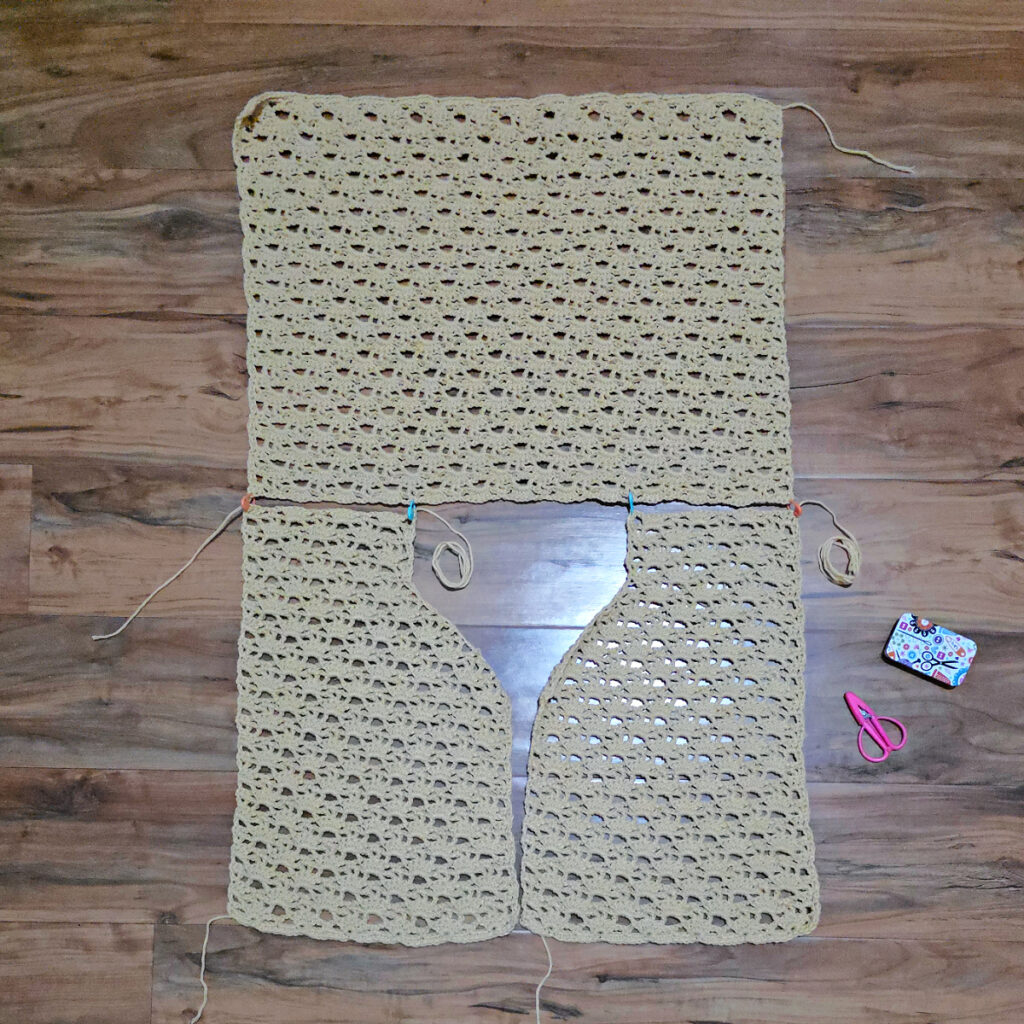 A beige colored cropped crochet cardigan in progress.