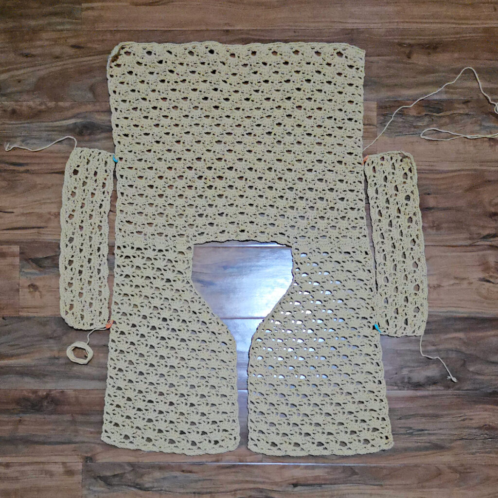 A beige colored cropped crochet cardigan in progress.