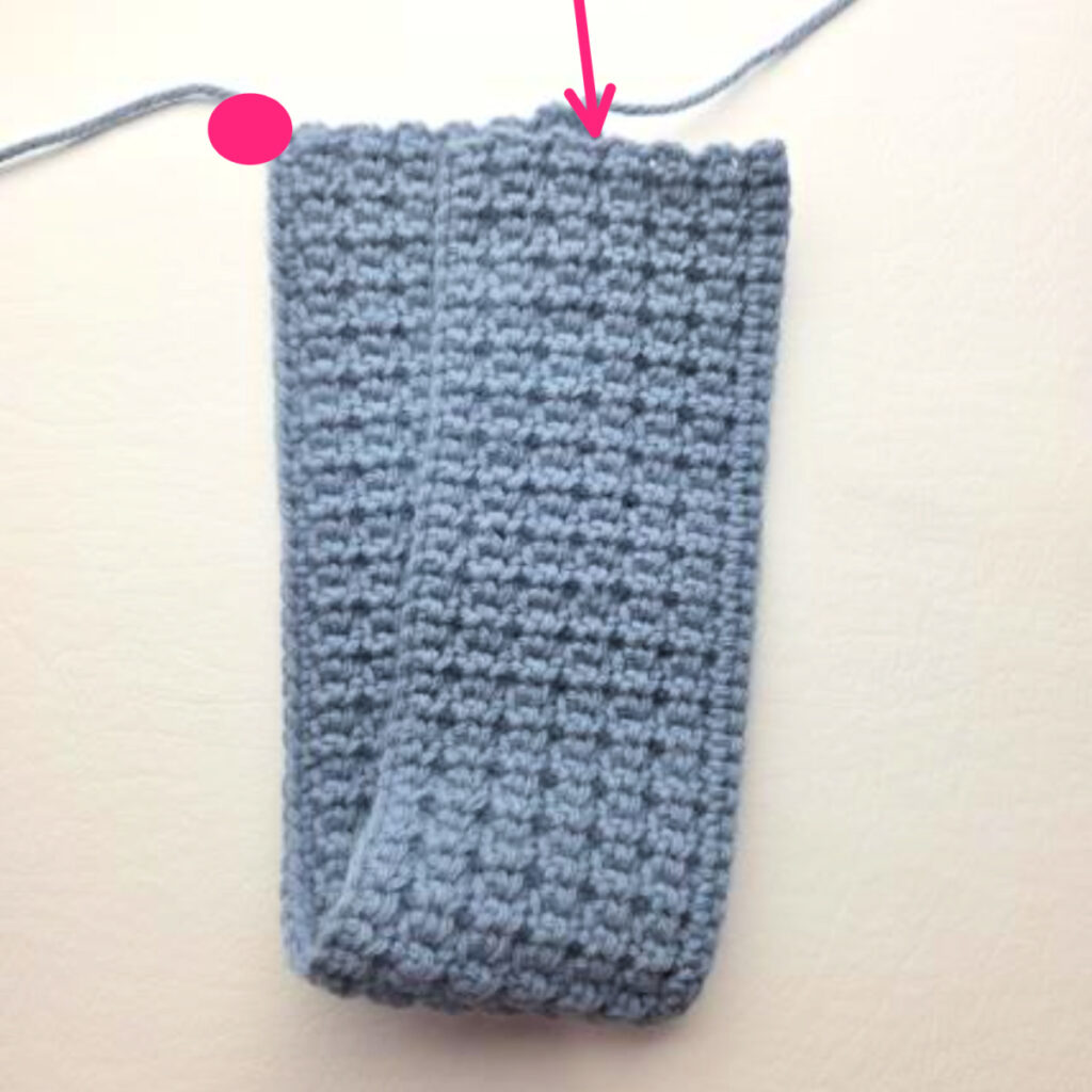 The ends of a handmade gray crochet ear warmer being stitched.