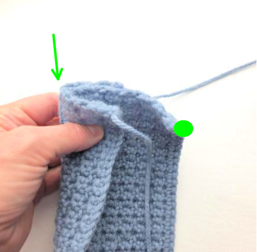 The ends of a handmade gray crochet ear warmer being stitched.