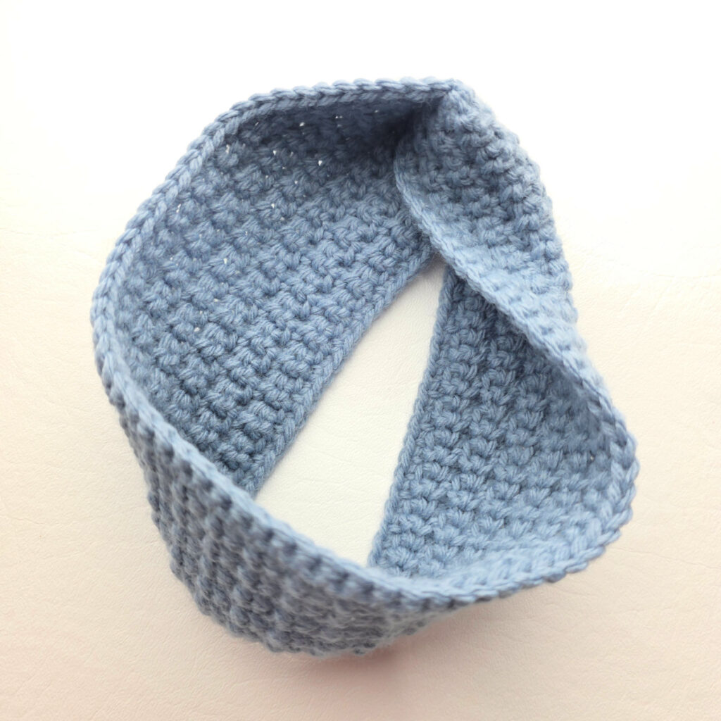 A gray crochet ear warmer against a white background.