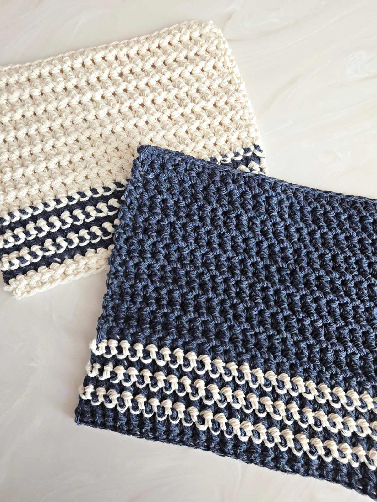 Blue and white crochet dishcloth against a marble background.