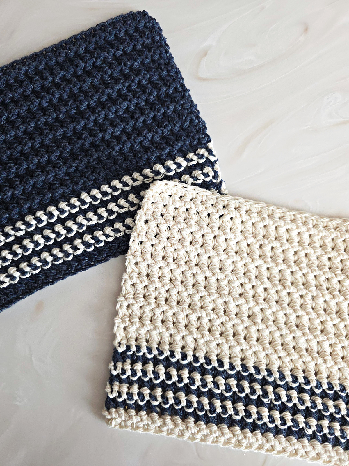 Blue and white crochet dishcloth against a marble background.