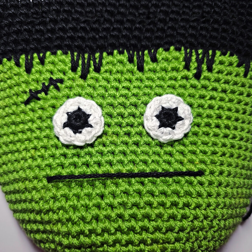 Crochet frankenstein's monster in green and black yarn.
