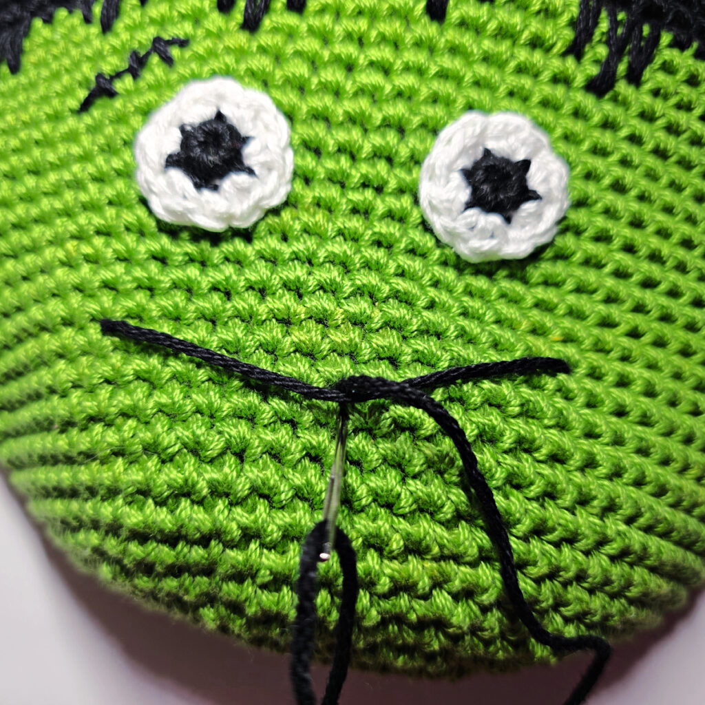 Crochet frankenstein's monster in green and black yarn.
