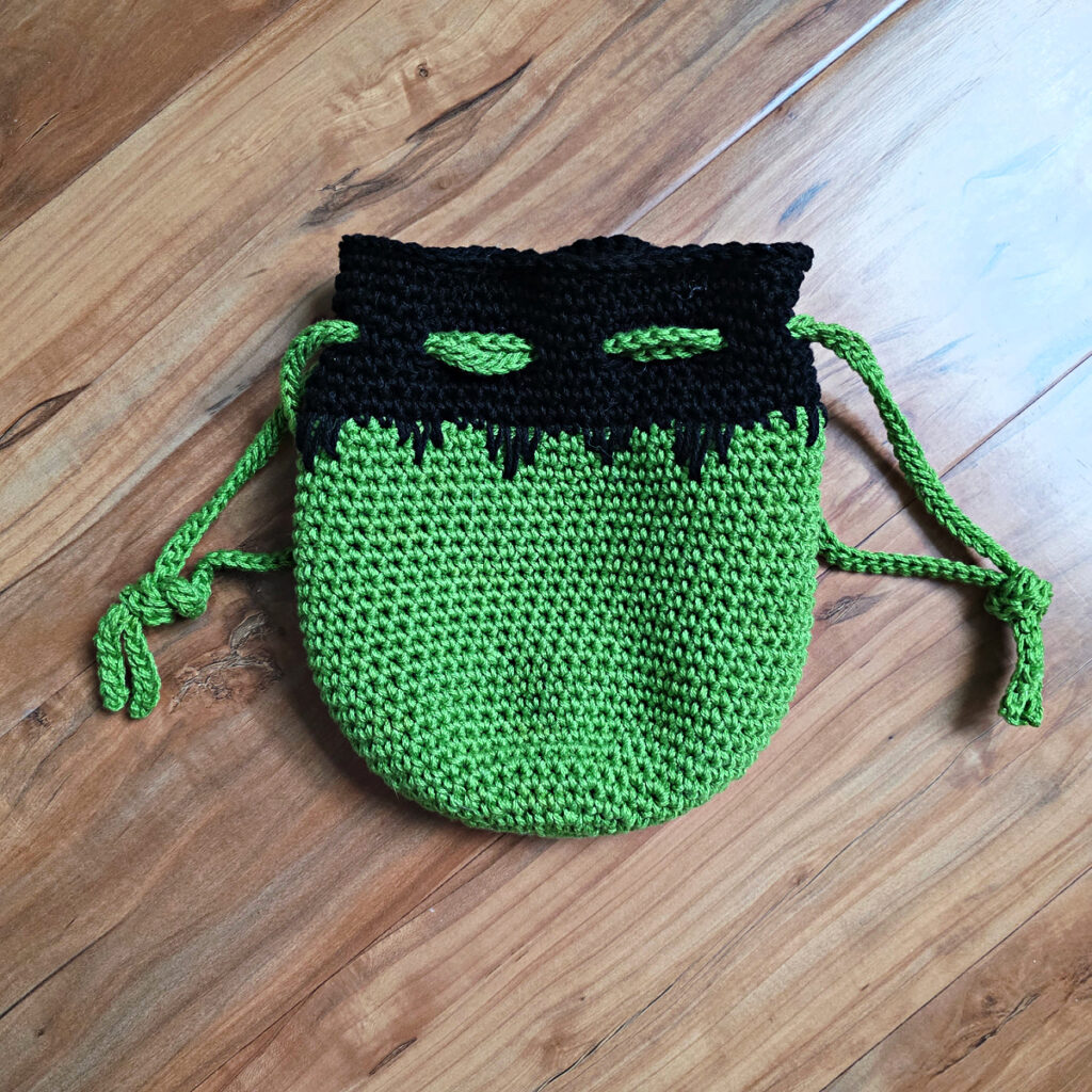 The body of a crochet monster treat bag on a wooden background.