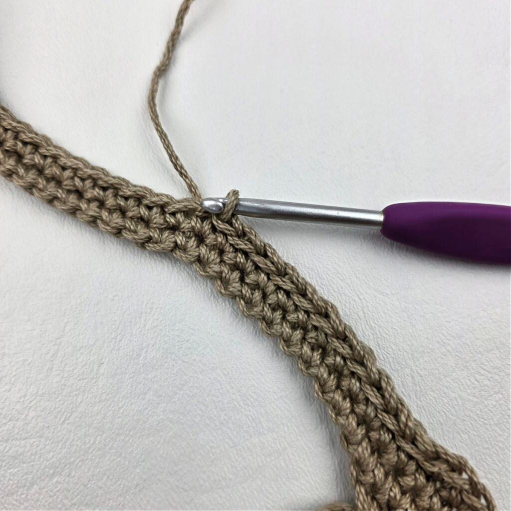 A crochet hook working a strap.