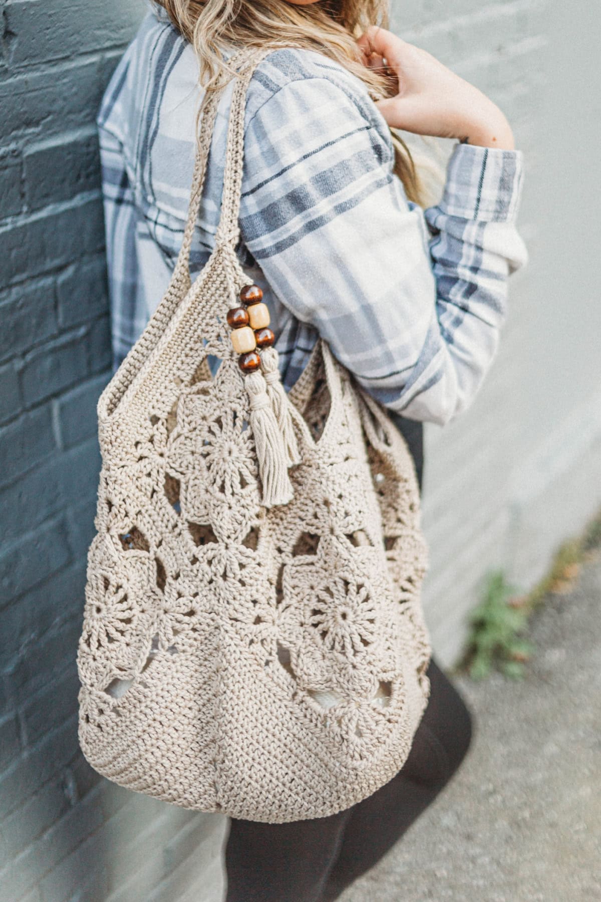 A girl wearing a striped shirt holding a crochet tote bag over her shoulder.