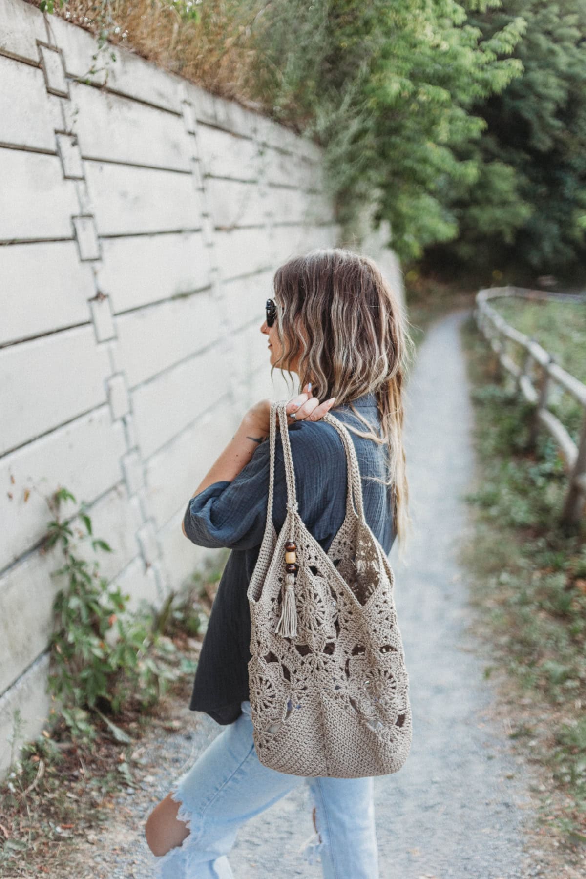 A girl with her back to the camera holding a crochet tote bag over her shoulder.