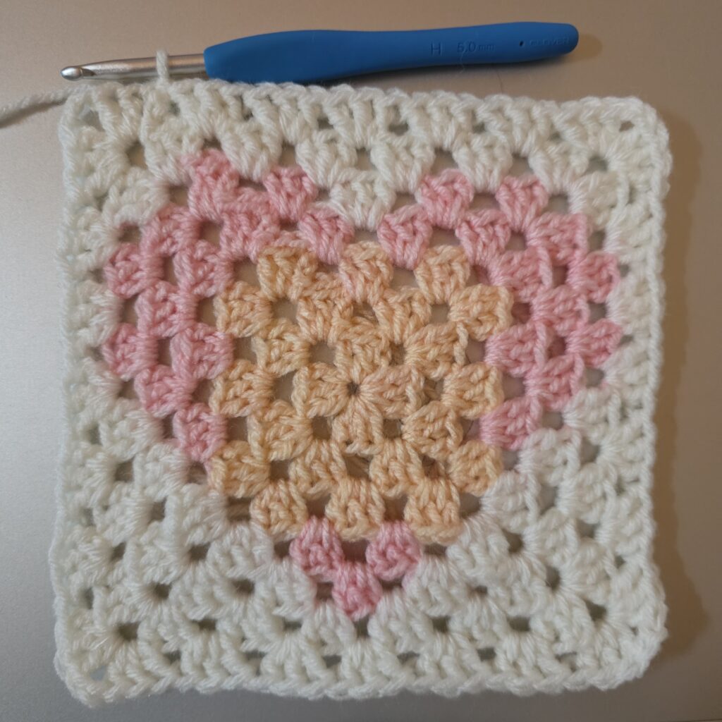 White granny square with a pink heart at the center.