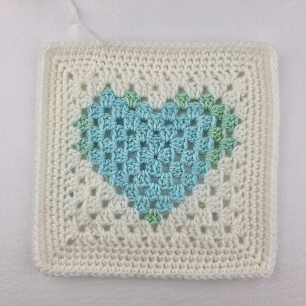 White granny square with a blue heart at the center.