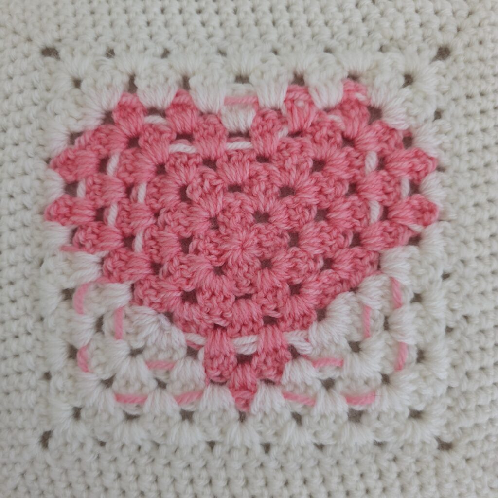 White granny square with a pink heart at the center.