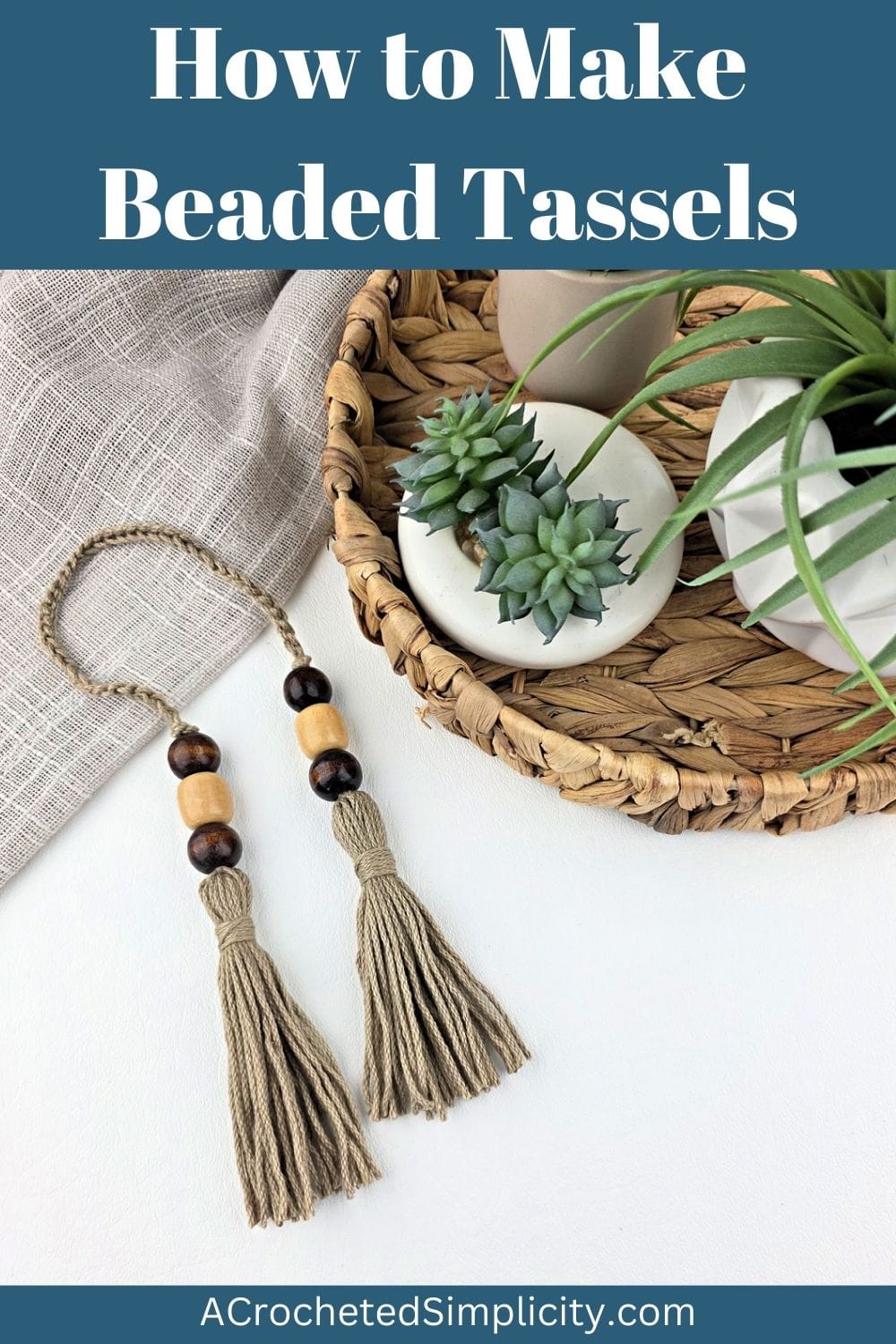 Two handmade yarn tassels with beads next to a basket of potted plants.