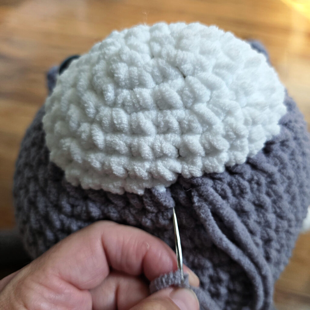 In process of assembling a crochet cat laying against a wooden floor.