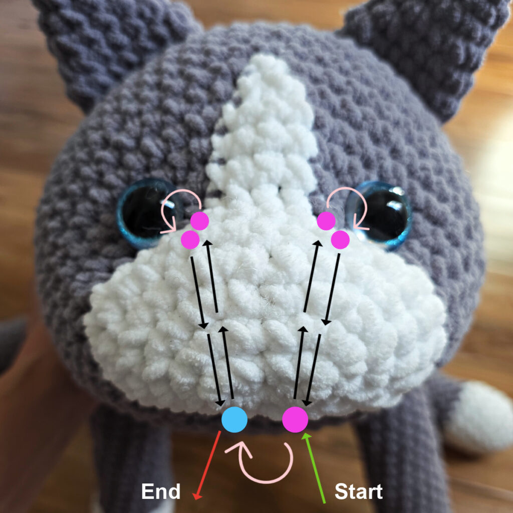 In process of assembling a crochet cat laying against a wooden floor.