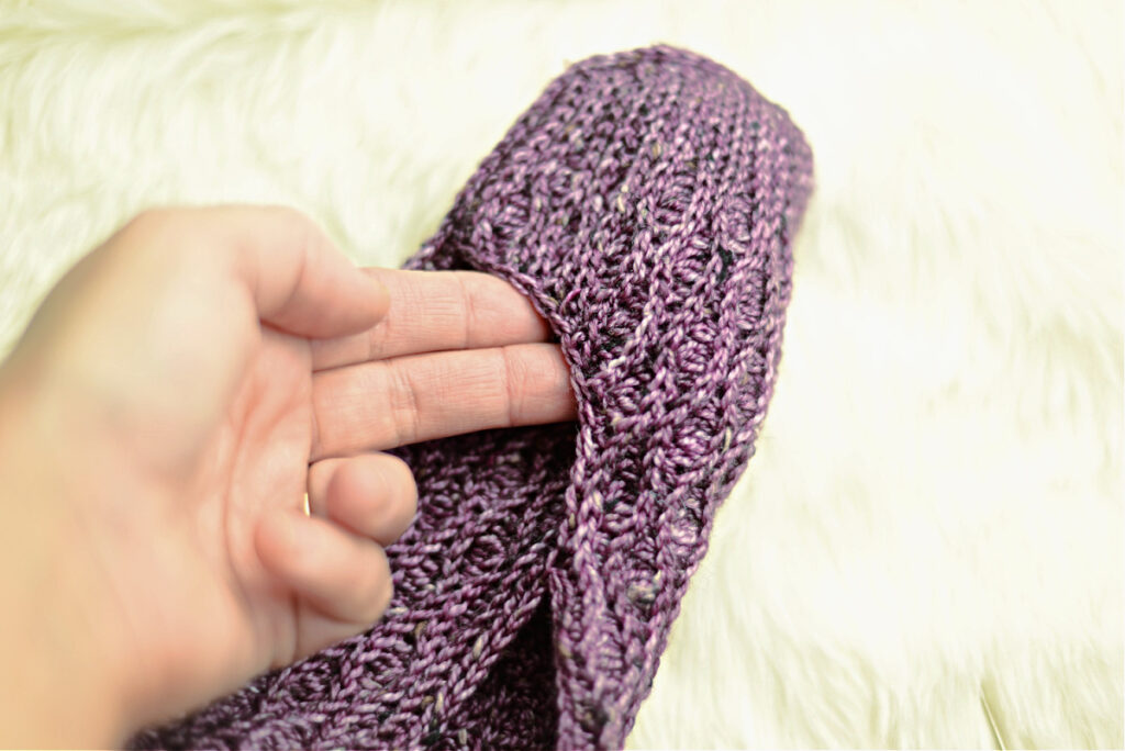Stitching a purple crochet kimono slipper.