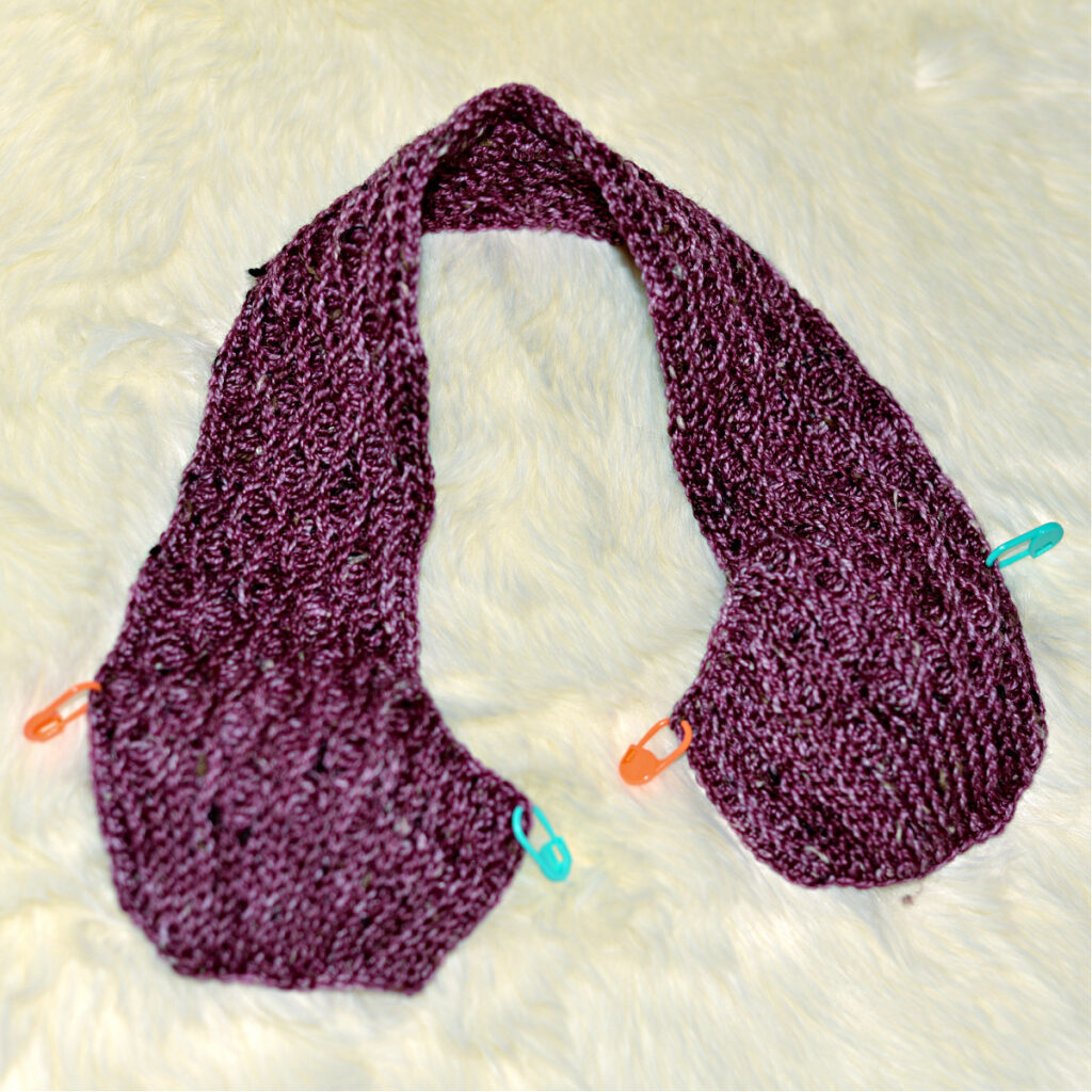 Stitching a purple crochet kimono slipper with stitch markers to hold it together.