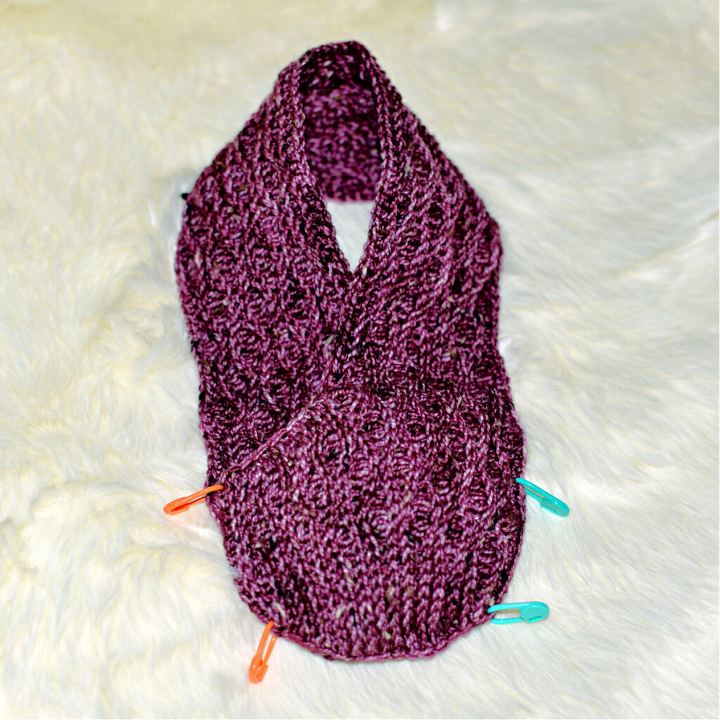 Stitching a purple crochet kimono slipper with stitch markers to hold it together.