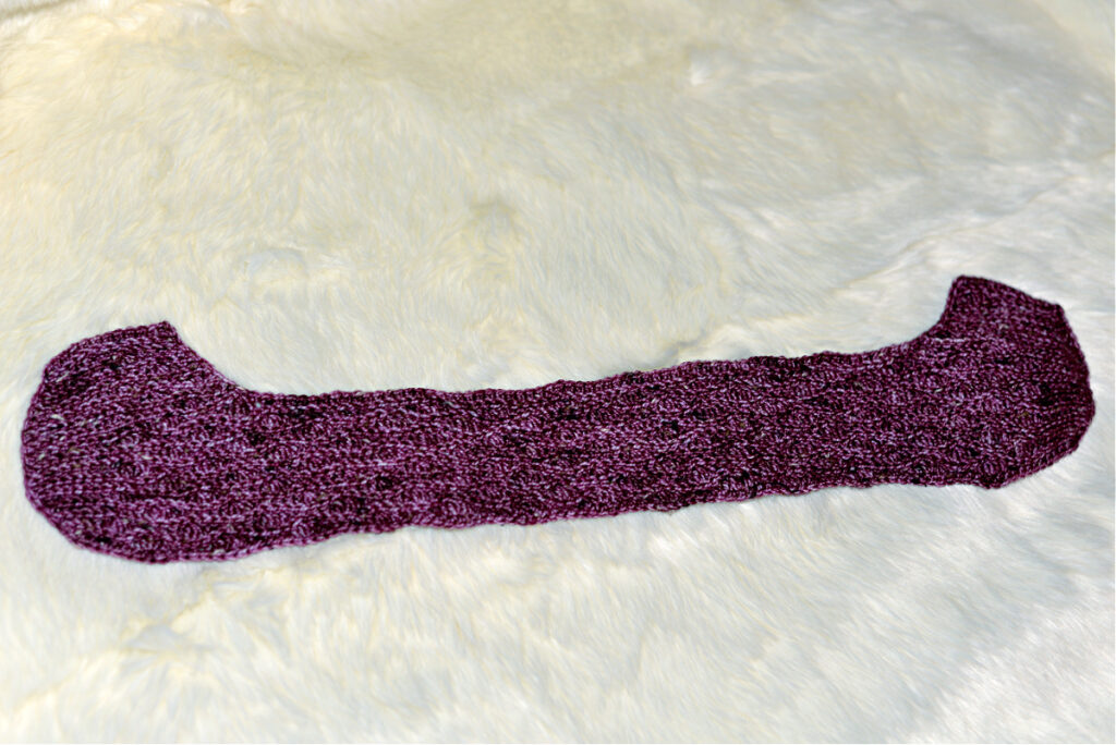 A purple crochet strip to form a kimono slipper against a white background.