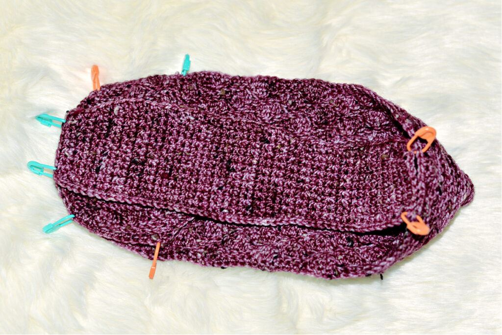 Stitching a purple crochet kimono slipper with stitch markers to hold it together.