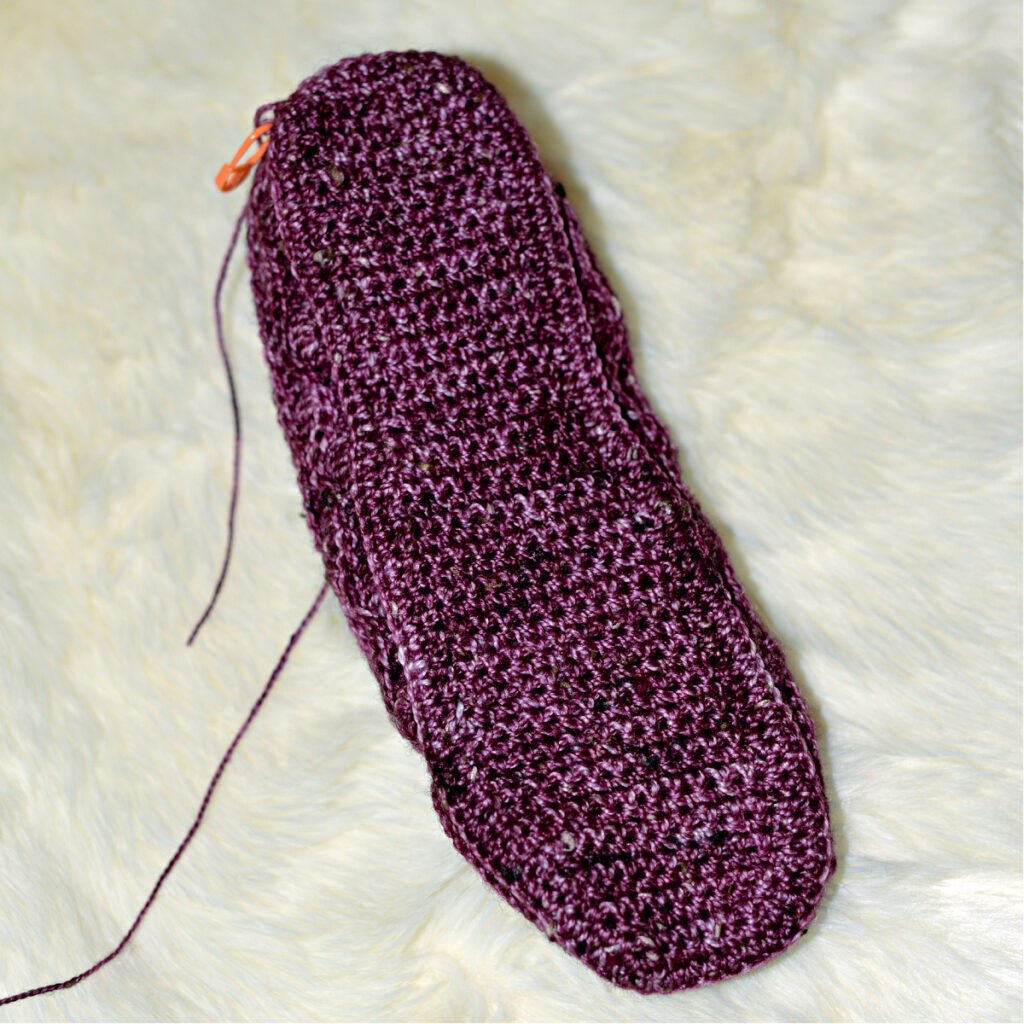 Stitching a purple crochet kimono slipper.