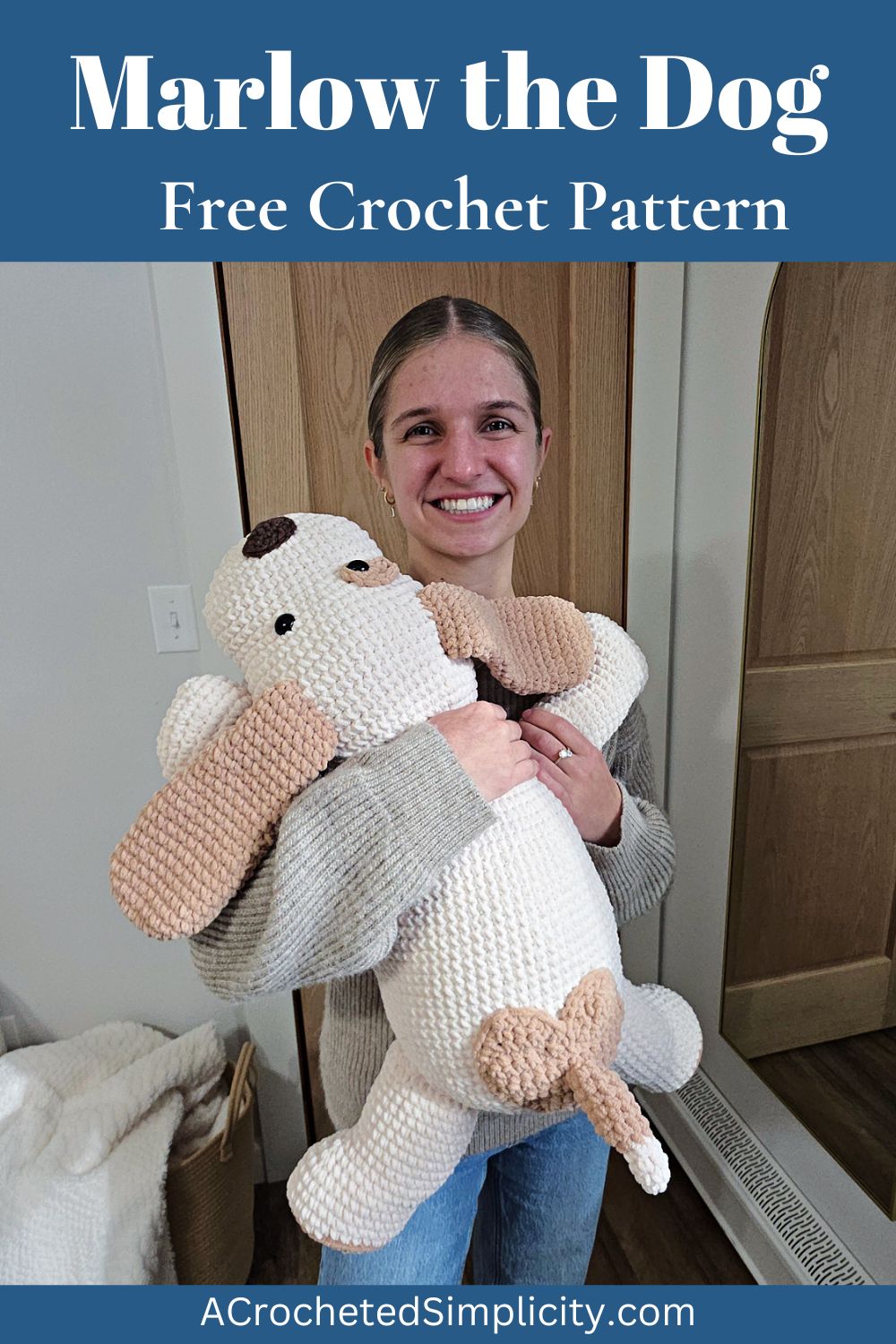 A girl holding a large plush white and brown crochet dog with floppy ears and a short tail.