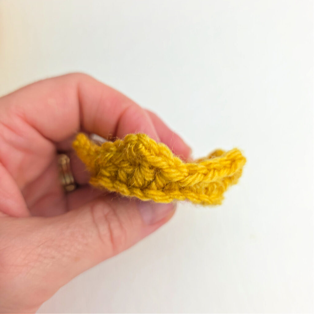 Front view of a completed crochet crown with gold yarn.