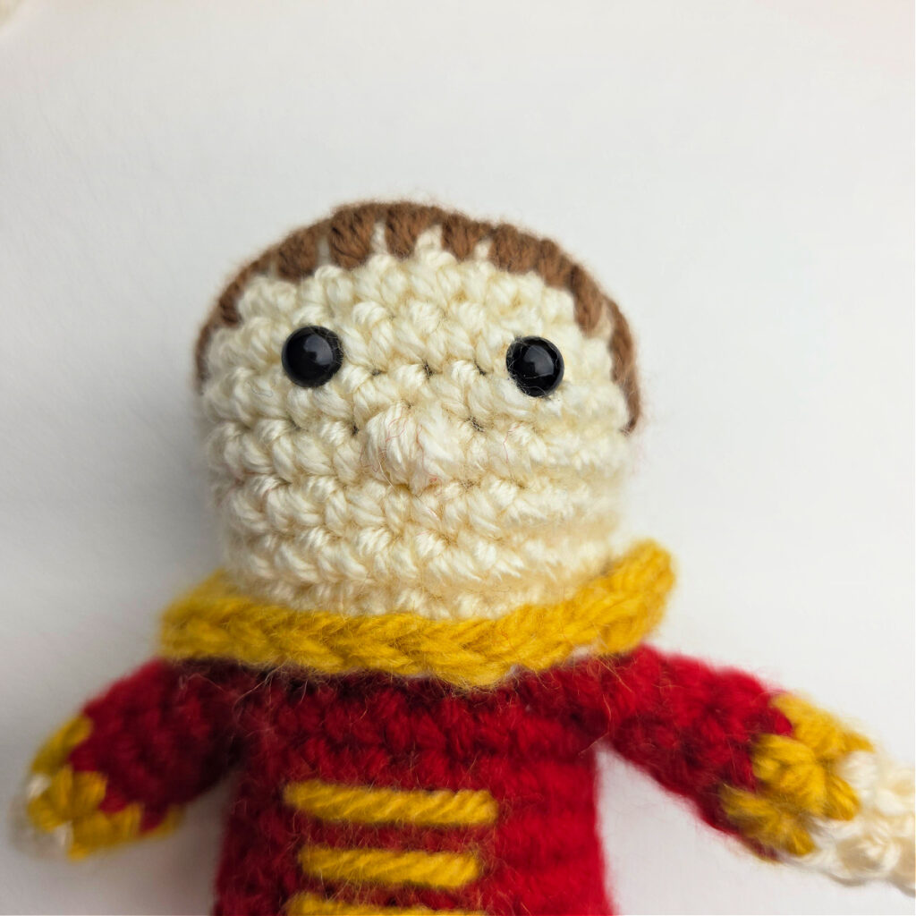 A photo that shows how and where to add a nose on a crochet nutcracker prince.