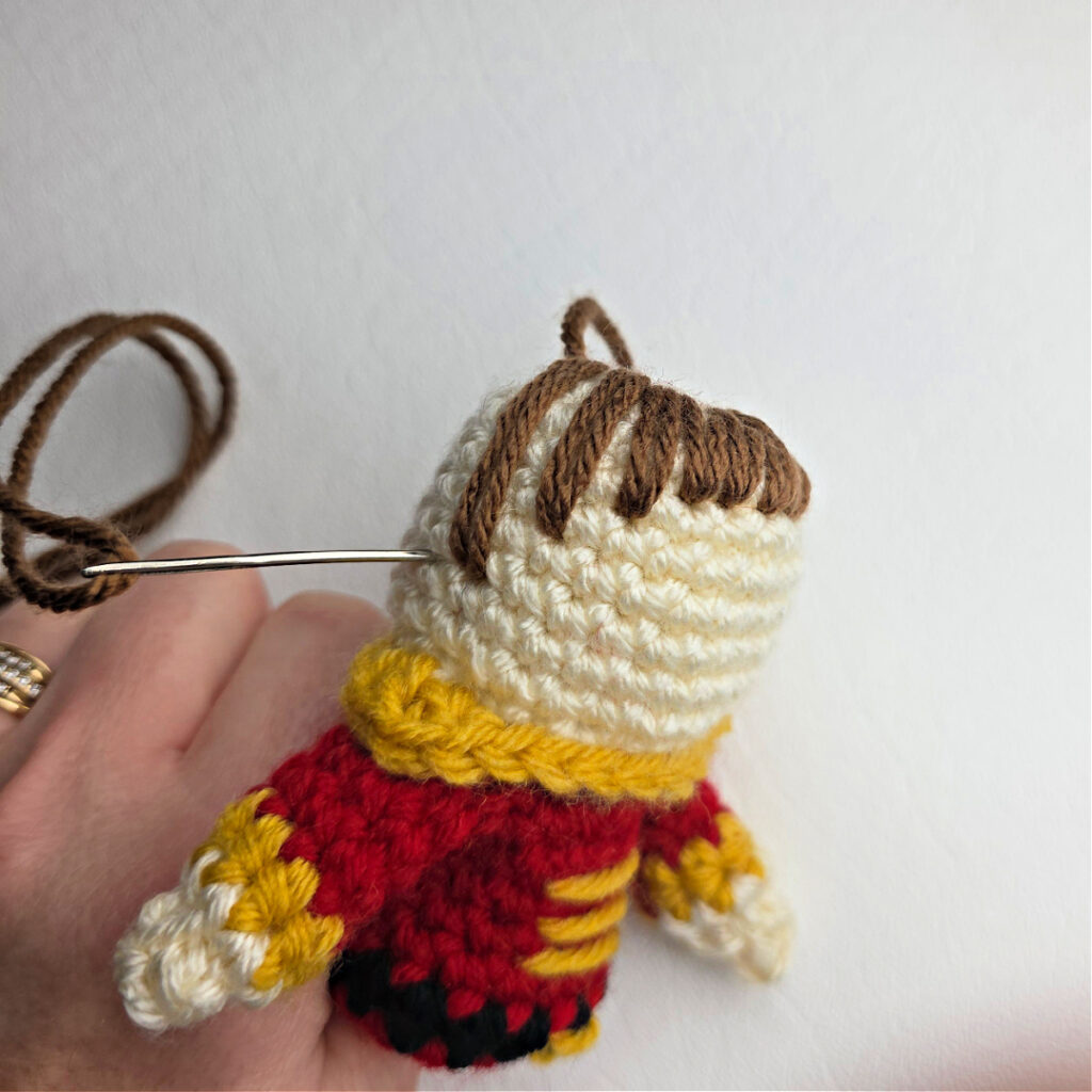 A side view of the nutcracker prince's hair being stitched on.