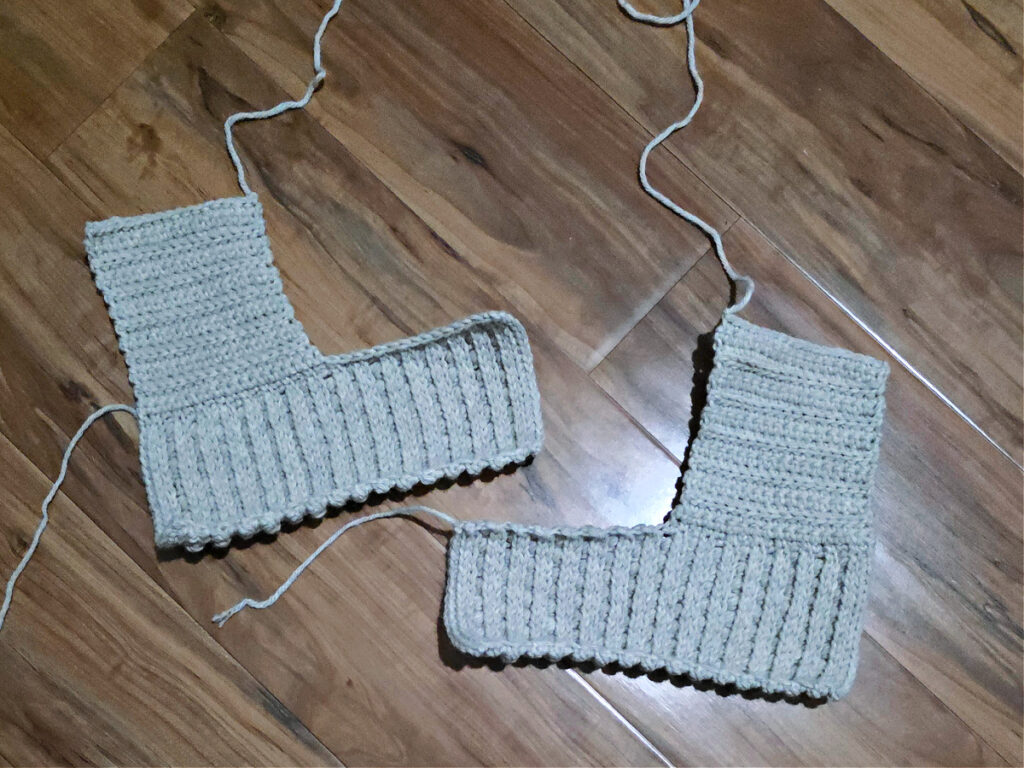 Two L-shaped grey crochet strips against a wooden floor.