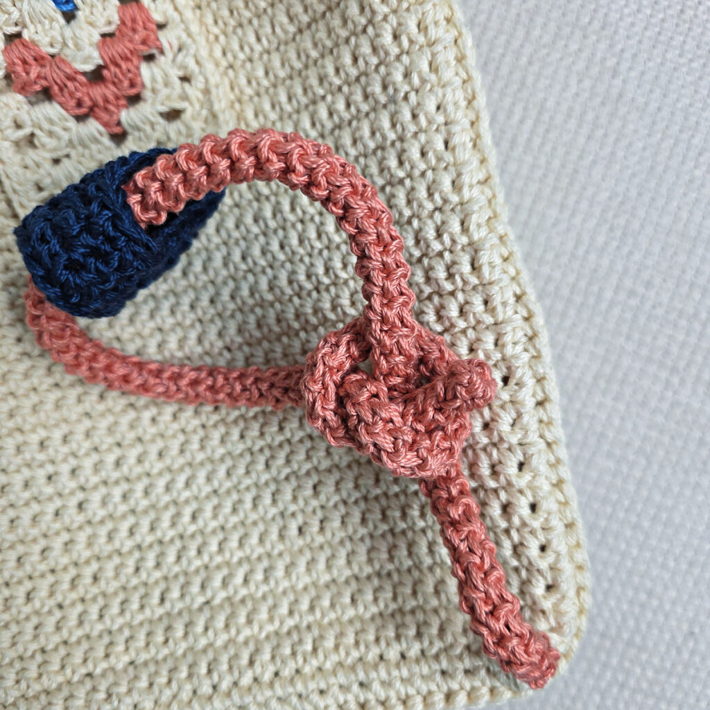 Attaching the button and strap to a crochet crossbody bag.