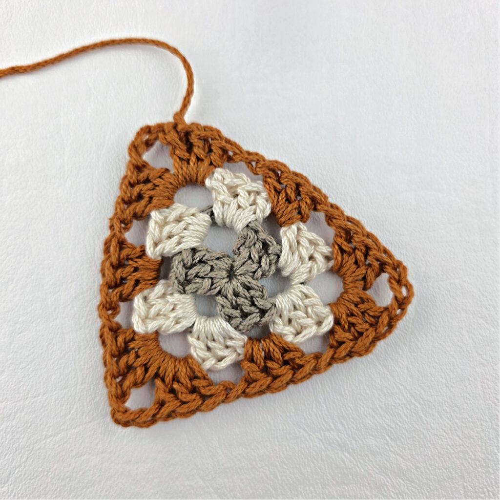 Round 3 of crochet granny stitch triangle.