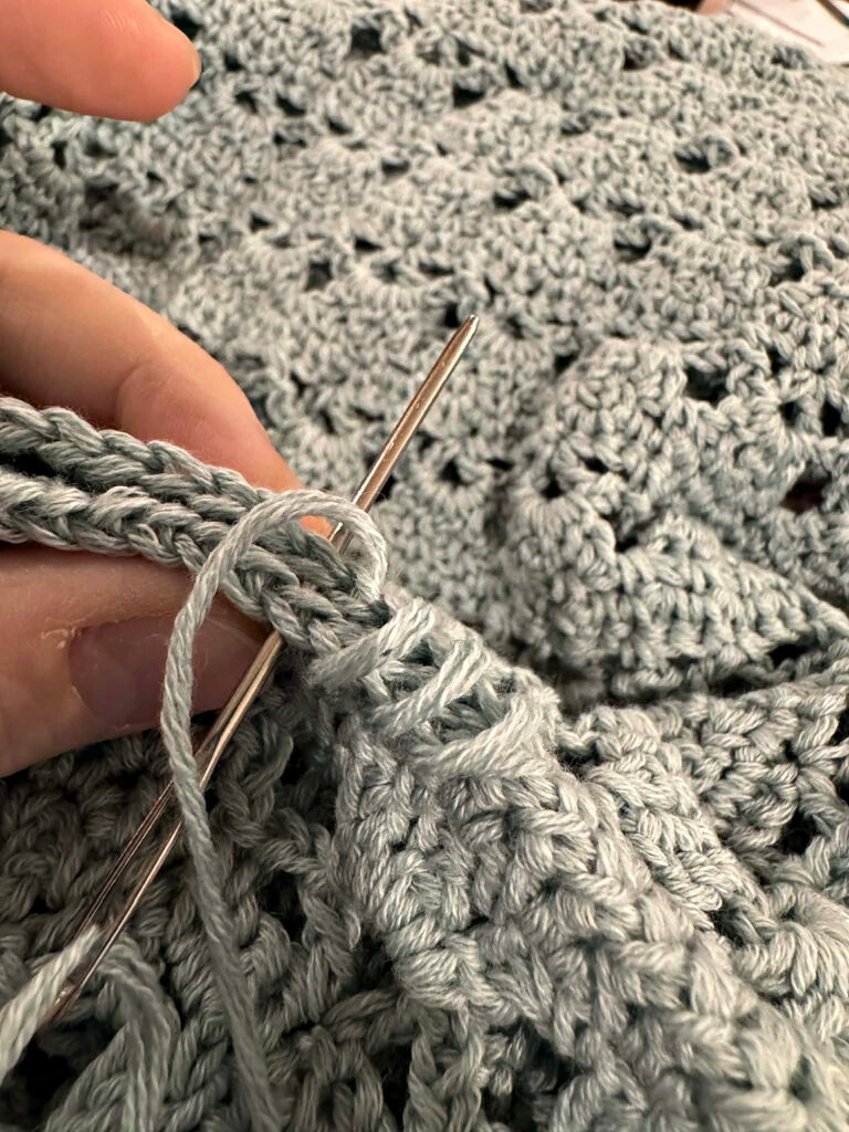 Seaming a blue summer crochet cardigan.