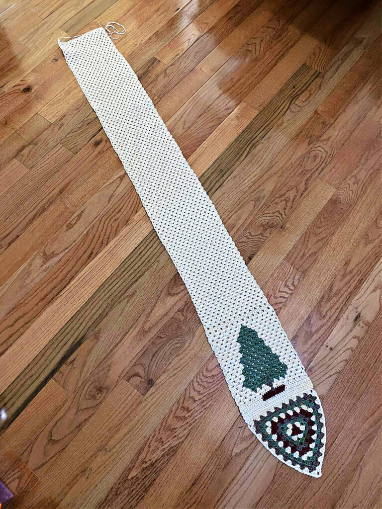 Crochet table runner with a granny stitch triangle and fir tree at the end.