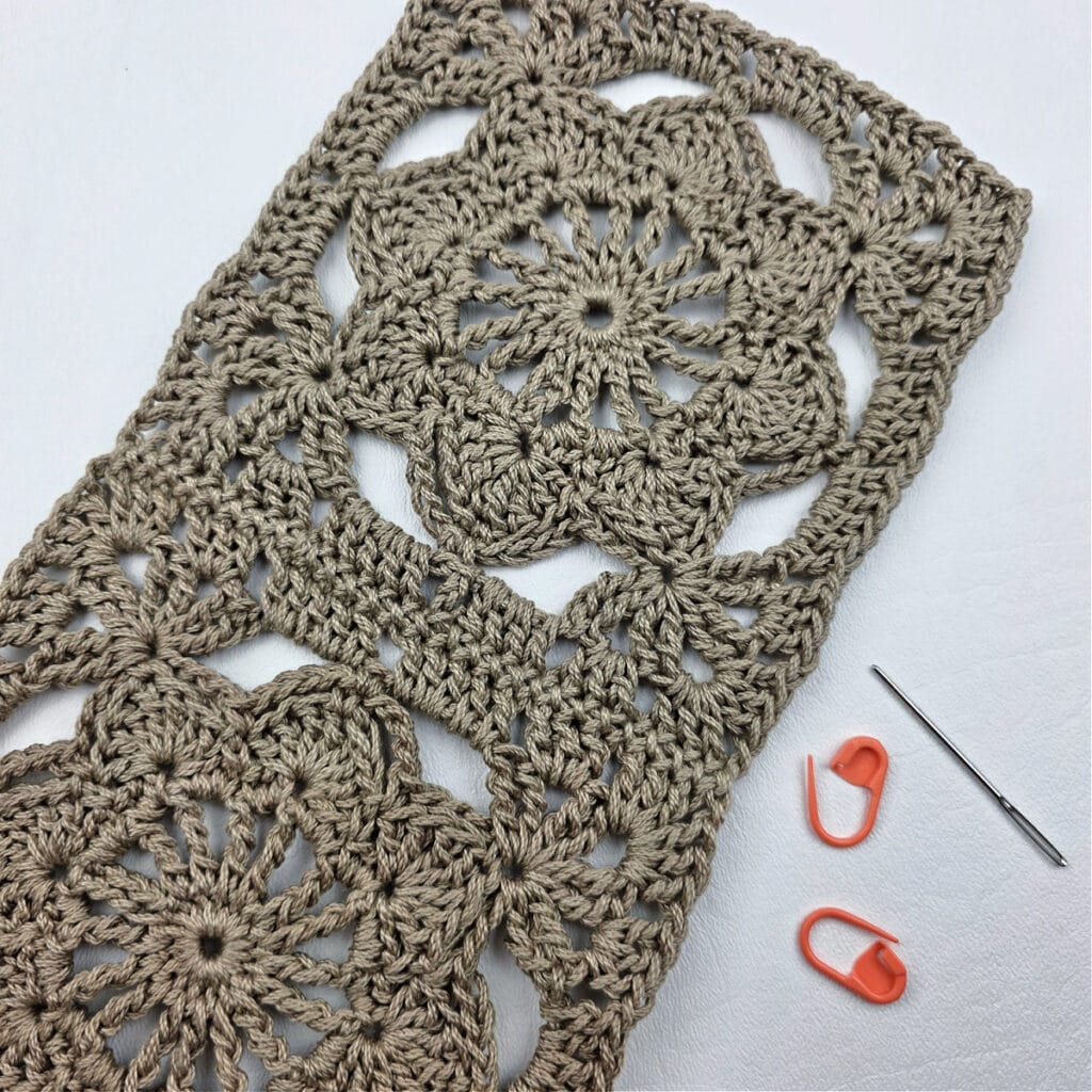 Joining crochet granny squares together with a stitch marker and needle.