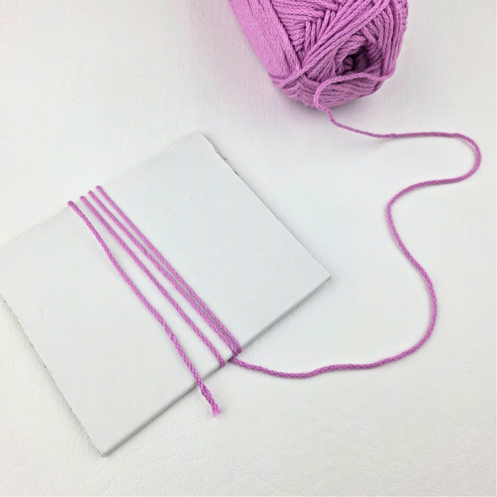 Pink yarn wrapped around a piece of paper.