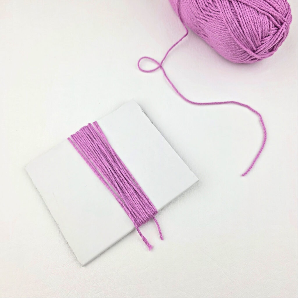 Pink yarn wrapped around a piece of paper.